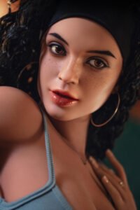 Close-up of a woman with dark curly hair, a black headband, and large hoop earrings, gazing softly to the side.