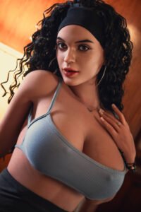 Close-up portrait of a woman with dark curly hair, a black headband, and a gray sports bra, looking at the camera with a confident expression.