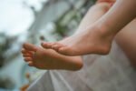 Close-up of bare feet resting on a ledge outdoors, with a soft, blurred background behind them.
